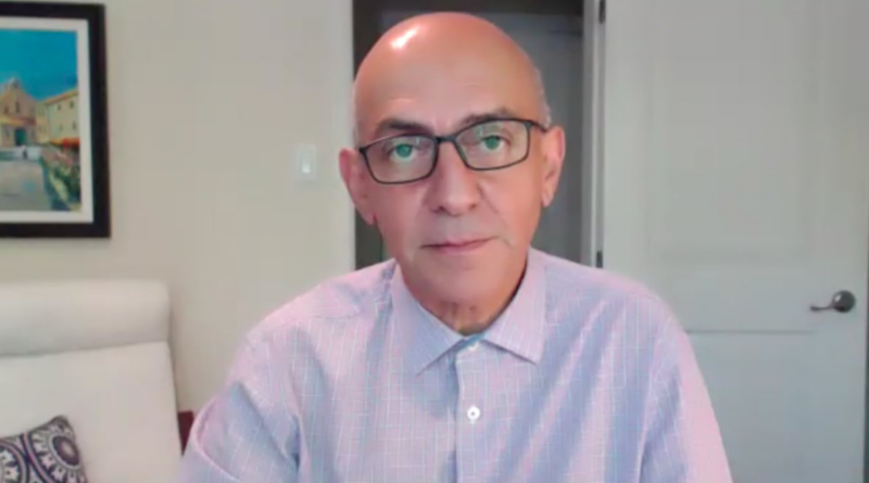 A man with a disruption of the sectaar glasses looks at the camera on video call.